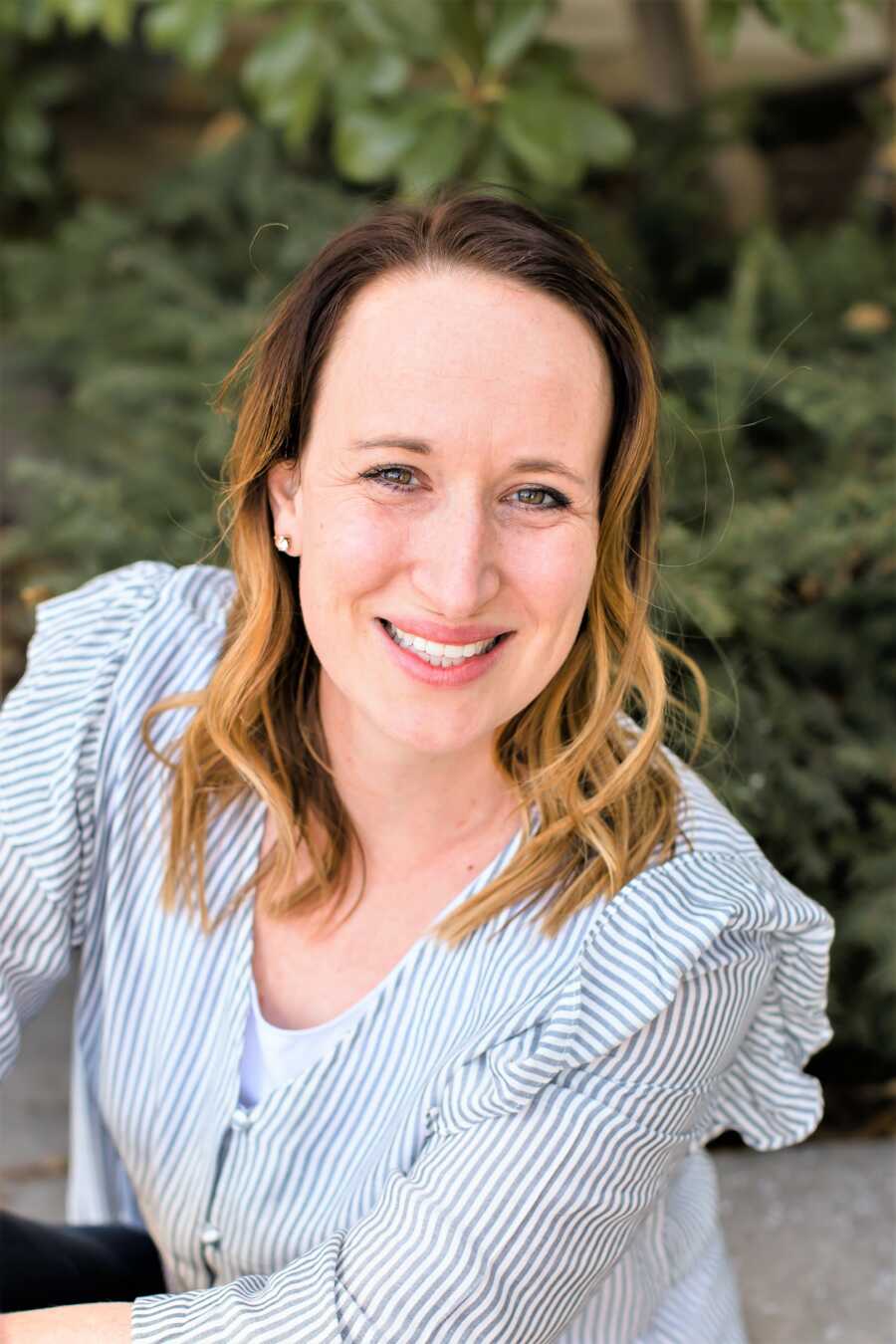 Portrait of a woman smiling with tree in the background